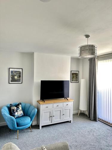 a living room with a tv and a blue chair at Beautifully Spacious 3 Bed Home in Kenton