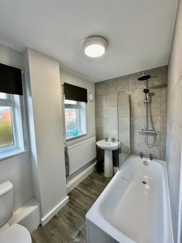 a white bathroom with a tub and a sink at Beautifully Spacious 3 Bed Home in Kenton