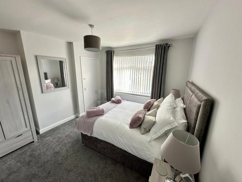 Un dormitorio con una cama con almohadas rosas y una ventana. en Beautifully Spacious 3 Bed Home, en Kenton
