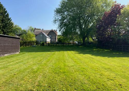 a large grass yard with a house in the background at Stylish 1-bed Cottage Escape in Piddlehinton in Piddlehinton