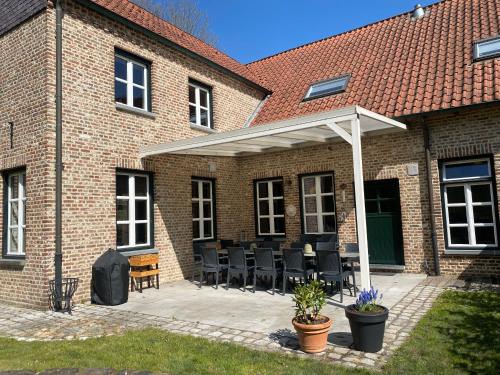a patio with a white pergola on a brick building at Landgoed De Hoogmolen in Oudsbergen 