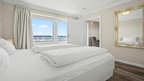 a bedroom with a large white bed and a window at Gurtdeel Käpitäns-Suite in Hörnum