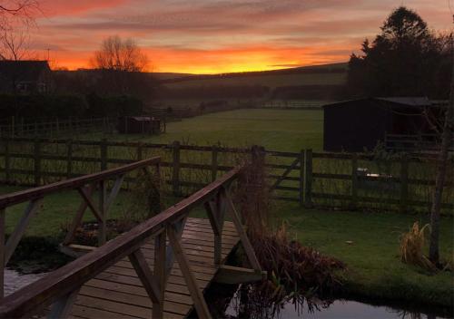a sunset over a wooden bridge with a fence at Stylish 1-bed Cottage Escape in Piddlehinton in Piddlehinton