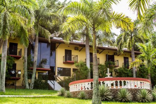 a yellow building with palm trees in front of it at Hotel e Pousada Recanto do Rio Pardo in São José do Rio Pardo