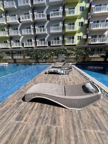 a swimming pool with a couch laying on the deck at Cozy & Convenient 1-Bedroom Condo 3 mins Away from the Airport in Lapu Lapu City