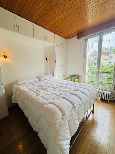 une chambre avec un grand lit avec un plafond en bois dans l'établissement Appartement Porte d'Orléans Paris, à Paris