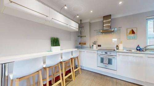 a kitchen with white cabinets and a counter with stools at Marina View Apartment in Swansea
