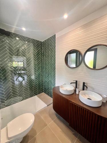 une salle de bain avec deux lavabos, un miroir et une baignoire dans l'établissement Maison Di Fiori, location neuve avec piscine, à Porto-Vecchio