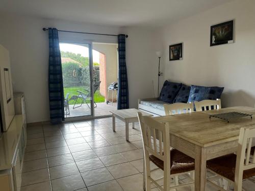un salon avec une table, des chaises et un canapé dans l'établissement PALMERAIE 412- piscine en résidence-clim-wifi, à Sari-Solenzara