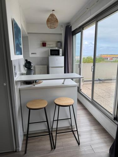 une cuisine avec deux tabourets et un comptoir avec un comptoir dans l'établissement Studio d Exception au Dernier Étage Terrasse et Vue Mer, à Dunkerque