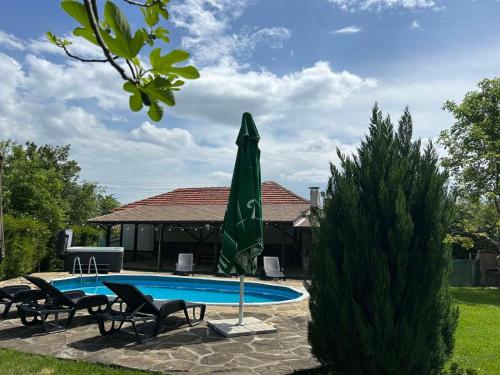 a pool with two chairs and a green umbrella at Къща за гости Вила Смокиня град Хисаря in Hisarya