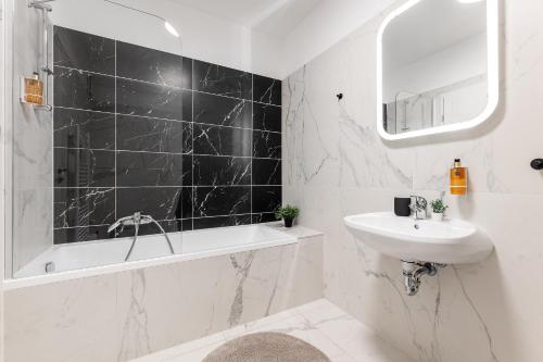 a white bathroom with a sink and a bath tub and a sink at Magnolia Apartment Hotel in Budapest