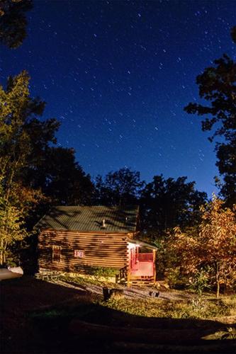an old log cabin under a night sky with stars at Deer To My Heart, Free Attraction Tickets, Hot Tub, Arcade, Air Hockey, WIFI!!! in Sevierville