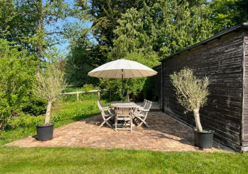 a patio with a table and chairs and an umbrella at Stylish 1-bed Cottage Escape in Piddlehinton in Piddlehinton