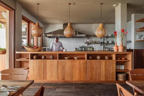 a kitchen with wooden cabinets and a man in the kitchen at Barracuda Boutique in Itacaré