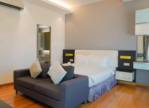 a bedroom with a bed and a couch at Naki Suites @ Silvertown in Phnom Penh