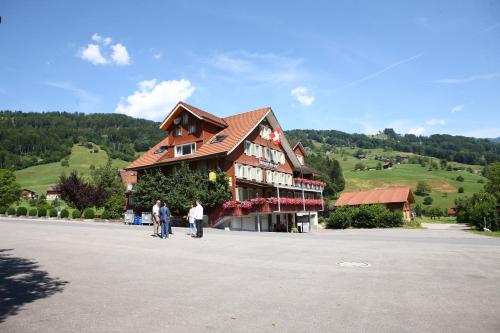 2 personnes marchant devant un grand bâtiment dans l'établissement Landgasthof Grossteil, à Giswil