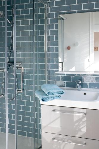 une salle de bain avec un lavabo et une douche avec du carrelage bleu dans l'établissement La Montpensier - maison dans le centre ville d'Eu, à Eu