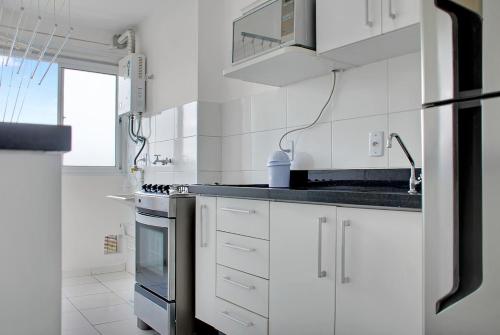a white kitchen with a stove and a refrigerator at 2 Bedrooms Cozy Parking in Carapicuíba