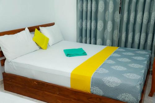 a bed with a blue and yellow blanket and pillows at Liyasha Hotel in Anuradhapura