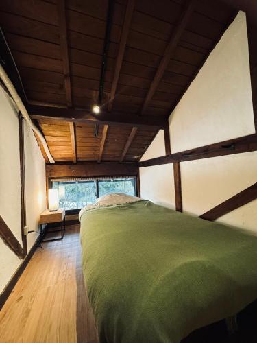 a bedroom with a bed in a room with wooden ceilings at Osugi-ya 大杉屋 in Wazuka