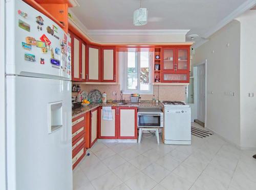a kitchen with red cabinets and a white refrigerator at enjoy in Cesme