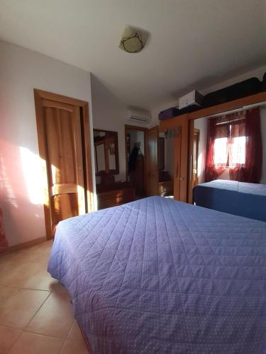 a bedroom with a large bed with a blue bedspread at Casa Vacanze TIO in Palmadula