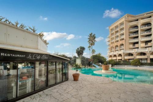 un hôtel avec une piscine à côté d'un bâtiment dans l'établissement Palm Beach 128 - Appartement dans résidence clim - wifi proche mer, à Cannes