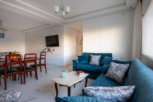a living room with blue couches and a table at Harhoura Val d'Or Grand Appart in Temara