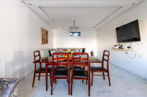a dining room with a table and chairs and a tv at Harhoura Val d'Or Grand Appart in Temara