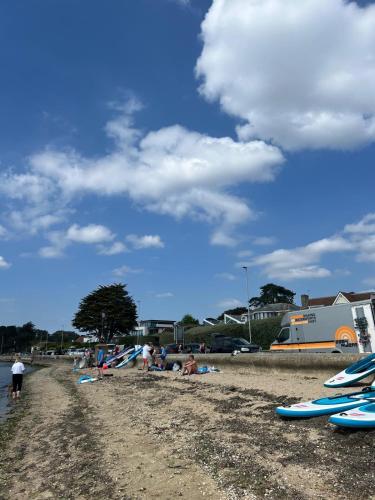 a group of people sitting on a beach with surfboards at Lilliput Village Canford Cliffs Salterns Marina&Harbour in Parkstone