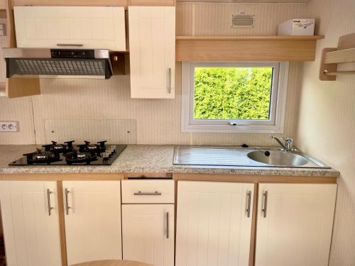 a kitchen with a sink and a stove and a window at Charmant Bungalow avec piscine et emplacement voiture in Yvoir