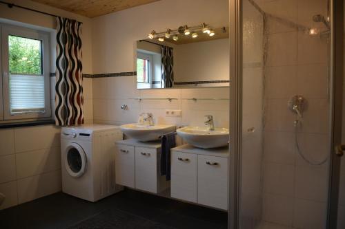 Un baño con dos lavabos y lavadora. en Haus Schwärzler, en Stiefenhofen