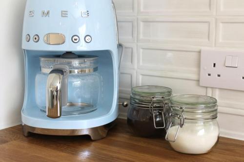 a blue mixer on a counter with jars of milk at Modern Country Cottage Stay in Lympsham