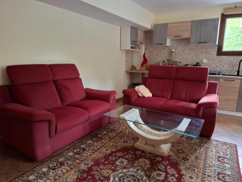 a living room with two red couches and a glass table at Gite OLIVIRA in Vesseaux