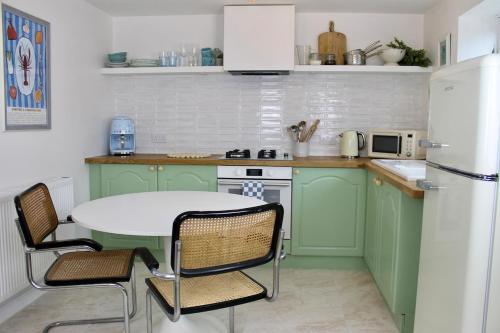 a kitchen with green cabinets and a white refrigerator at Modern Country Cottage Stay in Lympsham
