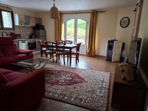 a living room with a red couch and a table and chairs at Gite OLIVIRA in Vesseaux