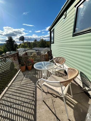 a patio with two chairs and a table on a balcony at Grannys Vintage Coastal Caravan in Kippford