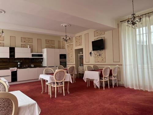 une salle à manger avec tables et chaises et une cuisine dans l'établissement Les Apparts'hôtel de Margot, à Courtenay