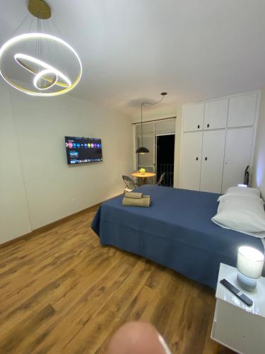a large bedroom with a blue bed and a table at Ap Smart Bosque in Campinas