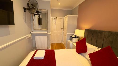 a small room with a bed with red pillows at Classic Hyde Park Hotel in London