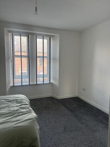 an empty bedroom with a bed and a window at Central 3-Bed Seaside Apartment - Sleeps 5 in Arbroath
