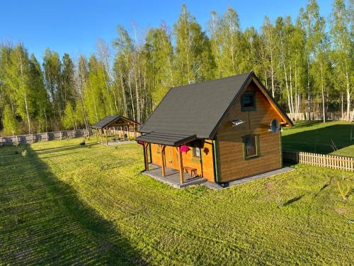 a cabin with a black roof on a grass field at Siedlisko Jaskółka - Puszcza Białowieska in Białowieża