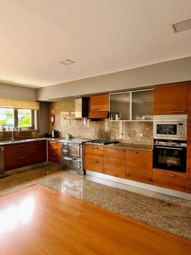 a large kitchen with wooden cabinets and stainless steel appliances at ToorgoHouse in Boticas