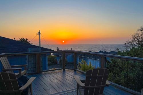 a deck with two chairs and a sunset at Salty Sunsets in Depoe Bay