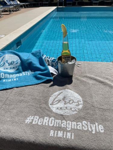 a bottle of champagne in a bucket next to a swimming pool at Hotel Apogeo - Breakfast Experience in Rimini