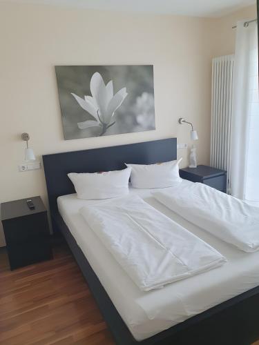 a bedroom with a large bed with white sheets at Hotel Sonnenhof in Illertissen