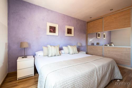 a bedroom with a large bed and a purple wall at Rent Top Apartments Rambla Catalunya in Barcelona