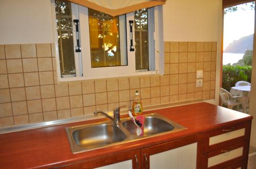 eine Küchentheke mit Spüle und zwei Fenstern in der Unterkunft Villa Takis - Kontogialos, Pelekas Beach in Pelekas