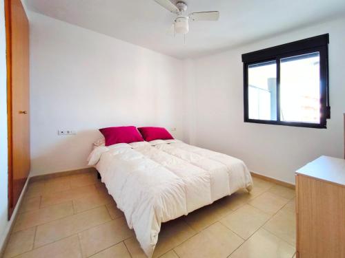una camera bianca con un grande letto con cuscini rossi di Apartamento con Terraza junto al Mar en Moncofa a Moncófar